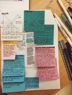 several pieces of paper on top of a wooden table with pens and pencils next to it