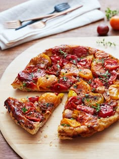 a pizza with tomatoes and herbs cut into slices on a cutting board next to other food items