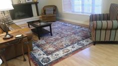 a living room filled with furniture and a rug on top of a hard wood floor