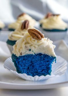 cupcakes with white frosting and blue icing, topped with pecans