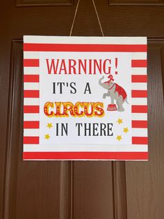 a circus sign hanging from a door with the words warning it's a circus in there