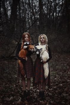 two women are standing in the woods with their stuffed animals and one is holding a fox