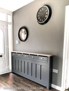 there is a clock on the wall next to a gray cabinet with drawers and doors