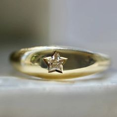 a yellow gold ring with a star on the front and center, sitting on a white surface