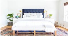 a bedroom with a bed, rug and window in the corner that has a blue headboard