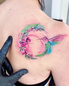 a woman with a tattoo on her back has a flower and bird design on her shoulder