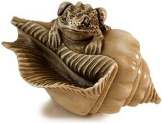 a frog sitting on top of a leaf shaped object in the shape of a shell