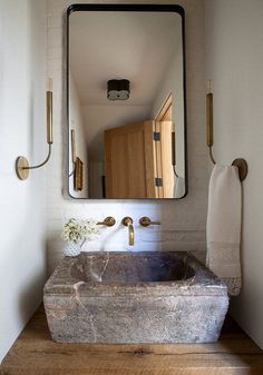 a bathroom sink sitting under a large mirror next to a wooden counter and wall mounted faucet