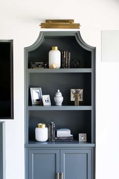 a gray bookcase with books and pictures on it