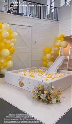 an open box with yellow and white balloons in the shape of a slide is on display