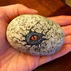 a hand holding a rock with a hole in it that looks like an eyeball