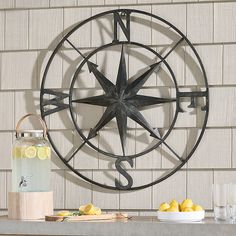 a large metal clock mounted to the side of a brick wall next to lemons