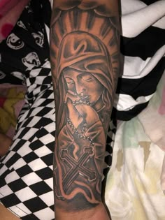 a person with a tattoo on their arm holding a cross and wearing a rosary in the other hand