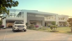 a white mercedes benz suv parked in front of a large house with trees and bushes