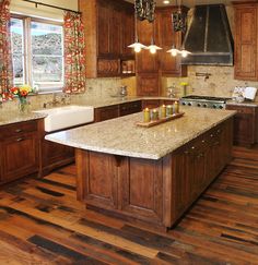 a large kitchen with wooden floors and granite counter tops on one side, an island in the other