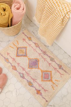 a bathroom with a rug, towels and slippers on the floor