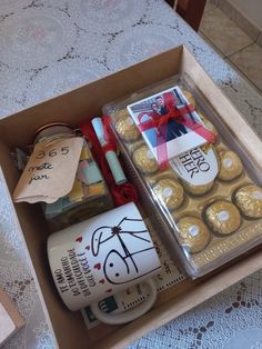 an open box filled with chocolates and wrapped in red ribbon on top of a table