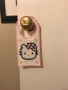 a hello kitty purse hanging on the wall next to a door knob with a gold bell