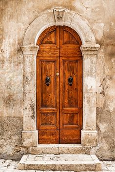 an old wooden door in front of a stone and stucco building with arched doorways