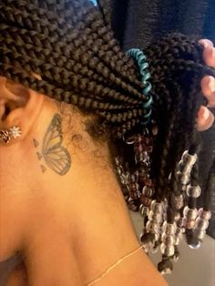 the back of a woman's head with braids and butterfly tattoos on it