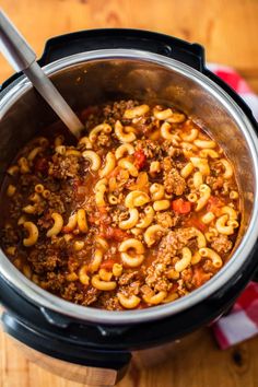 a slow cooker filled with macaroni and cheese on top of a wooden table