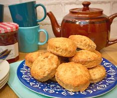 a blue plate topped with biscuits next to two mugs