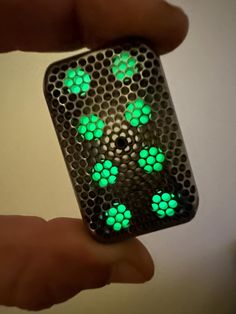 a person holding a cell phone with green lights on it's side and the case is shaped like hexagons