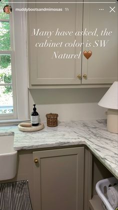 a kitchen with white cabinets and marble counter tops, along with a quote written on the wall