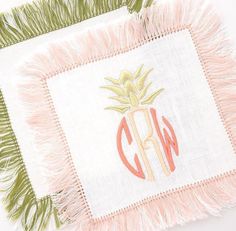 a pineapple embroidered onto a white piece of cloth with pink fringes on it