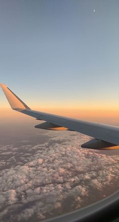 the wing of an airplane as it flies through the sky with clouds in the foreground