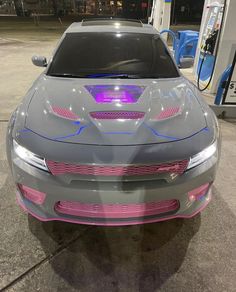 a gray and pink car is parked at a gas station