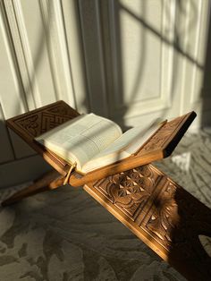 an open book sitting on top of a wooden bench in front of a white door