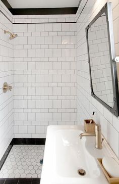 a white tiled bathroom with black and white floor tiles on the walls, along with two sinks