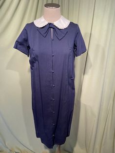 This is a cute vintage dress from the 60s. Label reads, Toni Lynn. Tagged a size 12. The bust measures 38", waist 40", see measurements below. I believe this is a maternity dress as the front button panel opens to reveal a generous pleat, to grow as you grow. Buttoned up it is a shift dress.  Made of blue cotton with a slight weave texture.  The dress is not lined.  It is short sleeve with a white Peter Pan style collar trimmed with a ball trim. Under the collar is a large bow. The buttons go all the way down the front & are covered in matching fabric. The dress slips over the head. The dress is in very good condition, no damage. No soil or stains.  Although this is a maternity dress, it is also a very nice shift dress! Charming! Measurements were taken with the garment lying flat. If you 90s Maternity Dress, Vintage Blue A-line Midi Dress, Blue Vintage A-line Midi Dress, Fitted Blue Dress With Doll Collar, Vintage Blue Dress With Doll Collar, Blue Knee-length Vintage Dress 1950s Style, Blue Knee-length 1950s Vintage Dress, Blue 1950s Style Knee-length Vintage Dress, 1970s Blue Fitted Dress