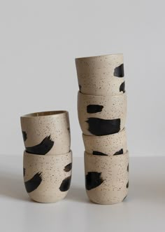 four black and white cups stacked on top of each other in front of a gray background