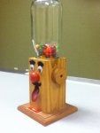 a wooden stand with a glass jar on top of it and a clown nose sticking out from the bottom