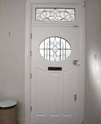 a white front door with a round window and side table on the floor next to it