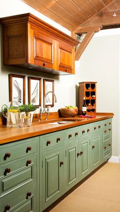 a kitchen with green cabinets and wooden counter tops