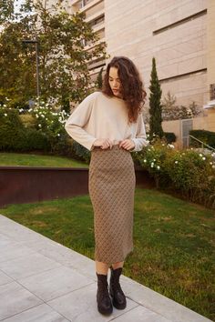 a woman standing in front of a building with her hands on her hips and looking at the camera