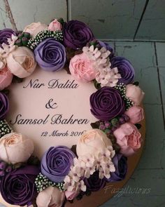 a wedding cake decorated with purple and pink flowers on top of a wooden board that says mr dalda & samol bahren