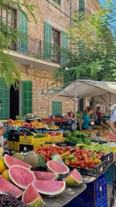 an outdoor market with watermelon, melons and other fruits