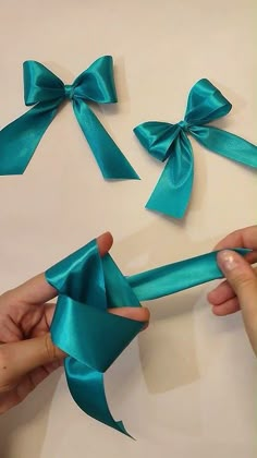 two hands holding blue ribbon with bows attached to the top and bottom of each bow