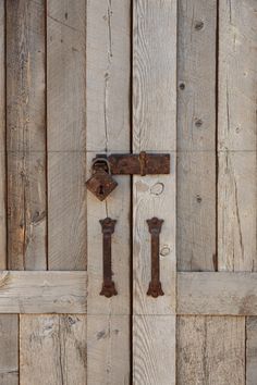 an old wooden door with two rusty latches