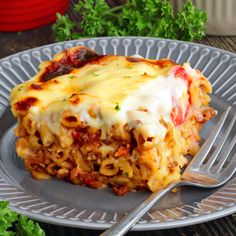 a slice of lasagna on a plate with a fork and parsley in the background