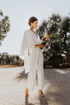 a woman in white jumpsuit holding flowers