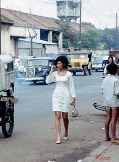 a woman walking down the street talking on her cell phone with two other people nearby