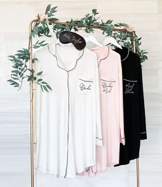 three women's shirts hanging on a clothes rack with greenery in the background