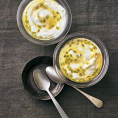 two bowls filled with food sitting on top of a table next to silver spoons