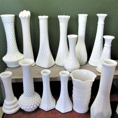 many white vases are lined up on a shelf