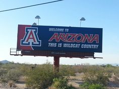 a large arizona ad on the side of a road in an arid area with trees and bushes